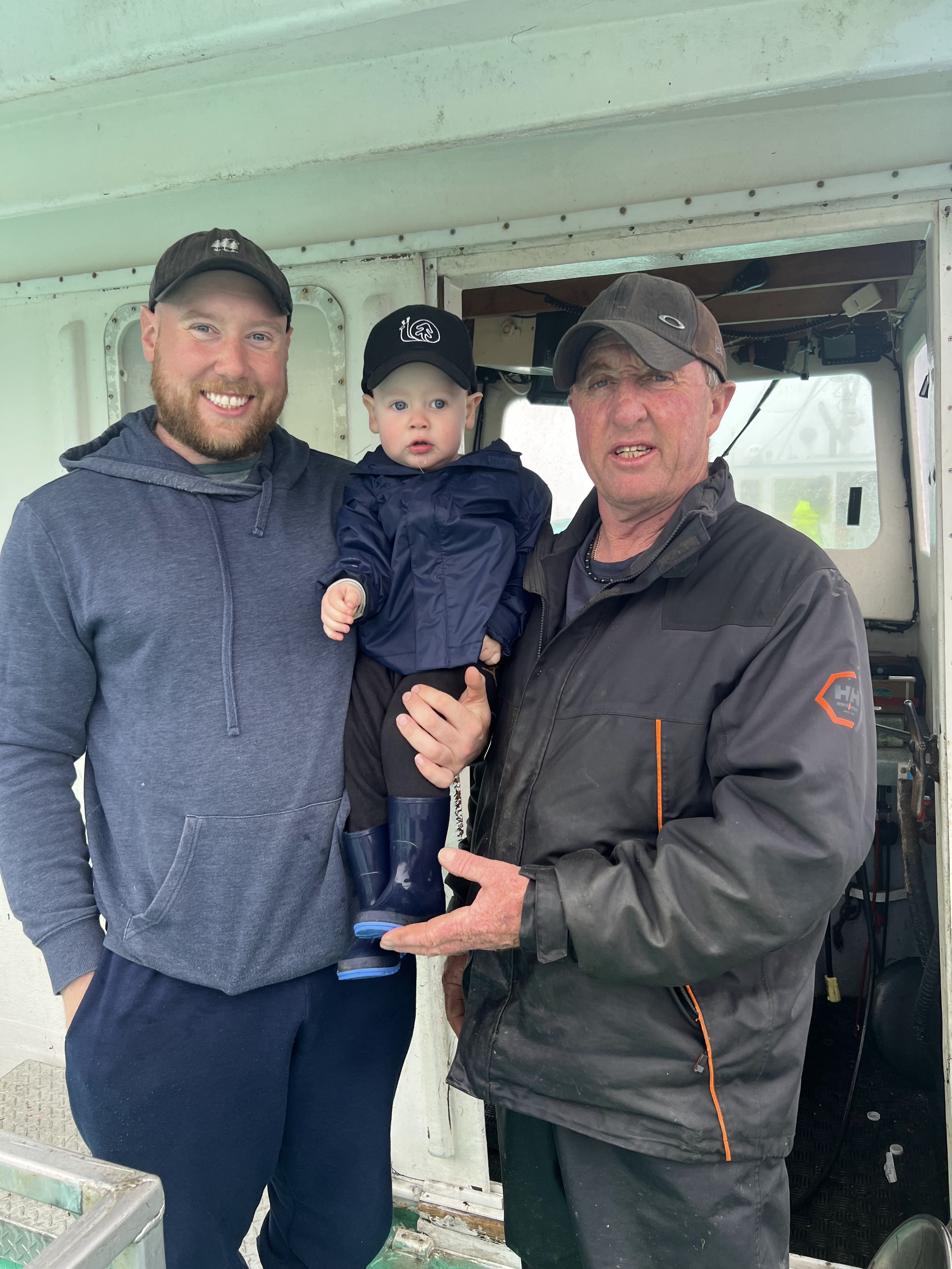 Four generations — Jonathon's father showing his infant son rope and trap gear in the fishing shed